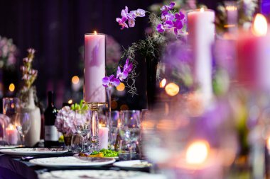 Şatafatlı yemek masaları ve cam eşyalar, bardağa şarap doldurmak. Güzel bulanık arkaplan. Tatil düğünü için hazırlık. Lüks bir restoran..