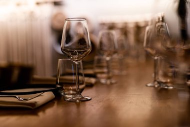 Şatafatlı yemek masaları ve cam eşyalar, bardağa şarap doldurmak. Güzel bulanık arkaplan. Tatil düğünü için hazırlık. Lüks bir restoran..