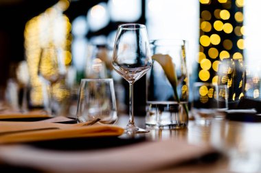 Şatafatlı yemek masaları ve cam eşyalar, bardağa şarap doldurmak. Güzel bulanık arkaplan. Tatil düğünü için hazırlık. Lüks bir restoran..