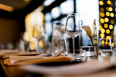 Şatafatlı yemek masaları ve cam eşyalar, bardağa şarap doldurmak. Güzel bulanık arkaplan. Tatil düğünü için hazırlık. Lüks bir restoran..