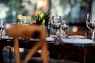 Şatafatlı yemek masaları ve cam eşyalar, bardağa şarap doldurmak. Güzel bulanık arkaplan. Tatil düğünü için hazırlık. Lüks bir restoran..
