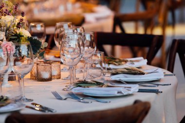 Şatafatlı yemek masaları ve cam eşyalar, bardağa şarap doldurmak. Güzel bulanık arkaplan. Tatil düğünü için hazırlık. Lüks bir restoran..