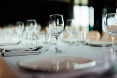 Şatafatlı yemek masaları ve cam eşyalar, bardağa şarap doldurmak. Güzel bulanık arkaplan. Tatil düğünü için hazırlık. Lüks bir restoran..