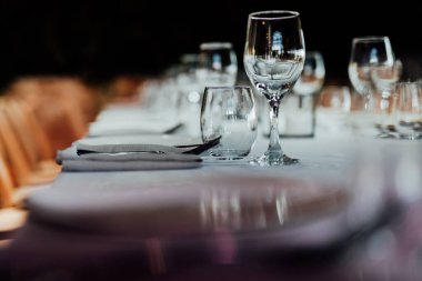 Şatafatlı yemek masaları ve cam eşyalar, bardağa şarap doldurmak. Güzel bulanık arkaplan. Tatil düğünü için hazırlık. Lüks bir restoran..