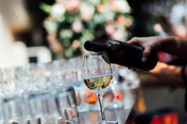 Şatafatlı yemek masaları ve cam eşyalar, bardağa şarap doldurmak. Güzel bulanık arkaplan. Tatil düğünü için hazırlık. Lüks bir restoran..