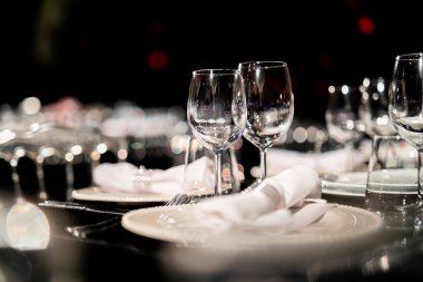 Şatafatlı yemek masaları ve cam eşyalar, bardağa şarap doldurmak. Güzel bulanık arkaplan. Tatil düğünü için hazırlık. Lüks bir restoran..