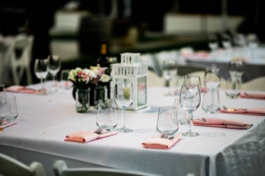 Şatafatlı yemek masaları ve cam eşyalar, bardağa şarap doldurmak. Güzel bulanık arkaplan. Tatil düğünü için hazırlık. Lüks bir restoran..