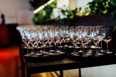 Şatafatlı yemek masaları ve cam eşyalar, bardağa şarap doldurmak. Güzel bulanık arkaplan. Tatil düğünü için hazırlık. Lüks bir restoran..