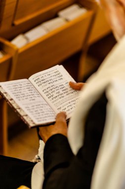 Yahudi adam, Bar Mitzvah kutlamasından önce İsrail sinagogunda Tevrat 'ı okumak için dua ediyor. Sağ tarafta Tefillin var..