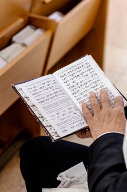 Yahudi adam, Bar Mitzvah kutlamasından önce İsrail sinagogunda Tevrat 'ı okumak için dua ediyor. Sağ tarafta Tefillin var..