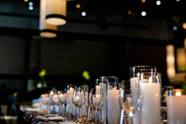 Şatafatlı yemek masaları ve cam eşyalar, bardağa şarap doldurmak. Güzel bulanık arkaplan. Tatil düğünü için hazırlık. Lüks bir restoran..