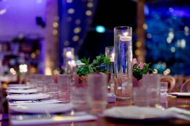 Şatafatlı yemek masaları ve cam eşyalar, bardağa şarap doldurmak. Güzel bulanık arkaplan. Tatil düğünü için hazırlık. Lüks bir restoran..