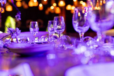 Şatafatlı yemek masaları ve cam eşyalar, bardağa şarap doldurmak. Güzel bulanık arkaplan. Tatil düğünü için hazırlık. Lüks bir restoran..