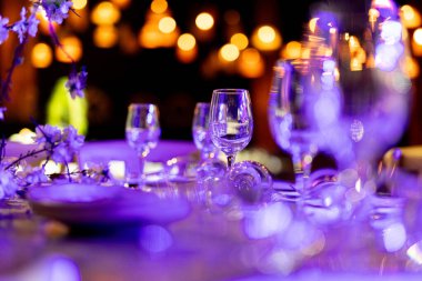 Şatafatlı yemek masaları ve cam eşyalar, bardağa şarap doldurmak. Güzel bulanık arkaplan. Tatil düğünü için hazırlık. Lüks bir restoran..