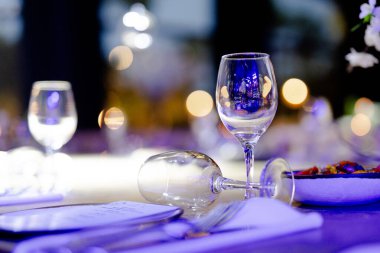 Şatafatlı yemek masaları ve cam eşyalar, bardağa şarap doldurmak. Güzel bulanık arkaplan. Tatil düğünü için hazırlık. Lüks bir restoran..