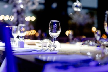 Şatafatlı yemek masaları ve cam eşyalar, bardağa şarap doldurmak. Güzel bulanık arkaplan. Tatil düğünü için hazırlık. Lüks bir restoran..