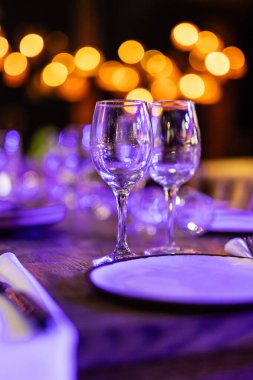 Şatafatlı yemek masaları ve cam eşyalar, bardağa şarap doldurmak. Güzel bulanık arkaplan. Tatil düğünü için hazırlık. Lüks bir restoran..