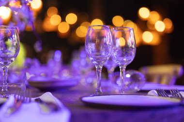 Şatafatlı yemek masaları ve cam eşyalar, bardağa şarap doldurmak. Güzel bulanık arkaplan. Tatil düğünü için hazırlık. Lüks bir restoran..