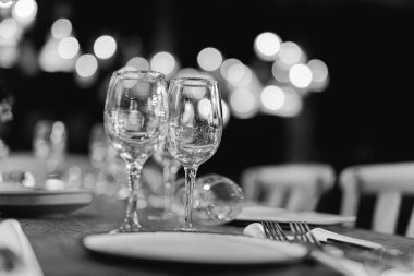 Şatafatlı yemek masaları ve cam eşyalar, bardağa şarap doldurmak. Güzel bulanık arkaplan. Tatil düğünü için hazırlık. Lüks bir restoran..