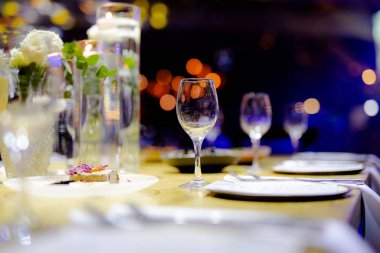 Şatafatlı yemek masaları ve cam eşyalar, bardağa şarap doldurmak. Güzel bulanık arkaplan. Tatil düğünü için hazırlık. Lüks bir restoran..