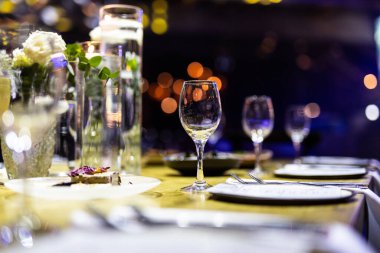Şatafatlı yemek masaları ve cam eşyalar, bardağa şarap doldurmak. Güzel bulanık arkaplan. Tatil düğünü için hazırlık. Lüks bir restoran..
