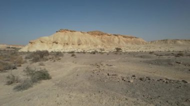 Engin İsrail çölünün çarpıcı 4K hava görüntüleri, geniş kum tepecikleri, engebeli kayalık arazi ve berrak çöl gökyüzünün altında geniş açık araziler. 