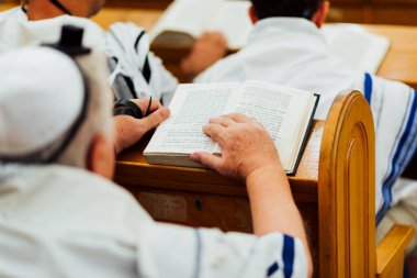 Yahudi adam, Bar Mitzvah kutlamasından önce İsrail sinagogunda Tevrat 'ı okumak için dua ediyor. Sağ tarafta Tefillin var..