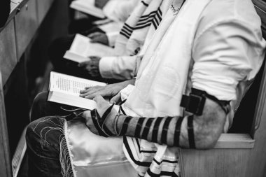 Yahudi adam, Bar Mitzvah kutlamasından önce İsrail sinagogunda Tevrat 'ı okumak için dua ediyor. Sağ tarafta Tefillin var..
