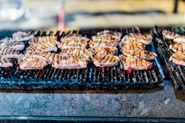 Bir barbekü etkinliği sırasında tahta kesme tahtasıyla taze dilimlenen sulu füme et eti. Yakın plan taze et, kavrulmuş bir kabuk, doğal ışık altında yakalanır. 