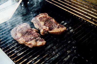 Bir barbekü etkinliği sırasında tahta kesme tahtasıyla taze dilimlenen sulu füme et eti. Yakın plan taze et, kavrulmuş bir kabuk, doğal ışık altında yakalanır. 