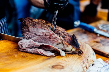 Bir barbekü etkinliği sırasında tahta kesme tahtasıyla taze dilimlenen sulu füme et eti. Yakın plan taze et, kavrulmuş bir kabuk, doğal ışık altında yakalanır. 