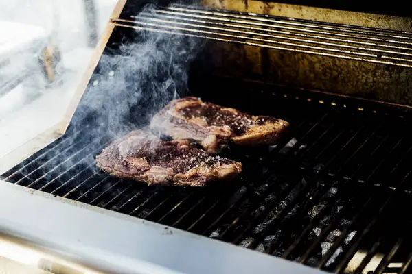 Bir barbekü etkinliği sırasında tahta kesme tahtasıyla taze dilimlenen sulu füme et eti. Yakın plan taze et, kavrulmuş bir kabuk, doğal ışık altında yakalanır. 