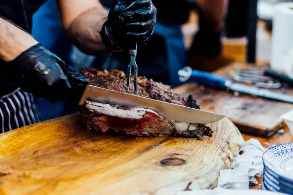 Bir barbekü etkinliği sırasında tahta kesme tahtasıyla taze dilimlenen sulu füme et eti. Yakın plan taze et, kavrulmuş bir kabuk, doğal ışık altında yakalanır. 