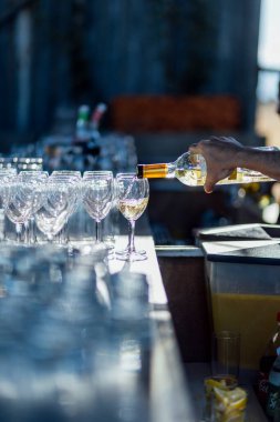 Şarap kadehleri ve çiçekli yemek masası, düğün için mükemmel, zarif bir parti ya da açık hava kutlaması için. Sıcak ışıklar ve yumuşak bokeh samimi ve lüks bir atmosfer yaratır..