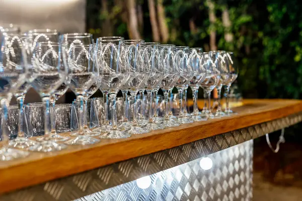 Şarap kadehleri ve çiçekli yemek masası, düğün için mükemmel, zarif bir parti ya da açık hava kutlaması için. Sıcak ışıklar ve yumuşak bokeh samimi ve lüks bir atmosfer yaratır..