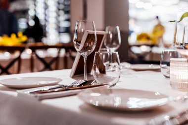 Şarap kadehleri ve çiçekli yemek masası, düğün için mükemmel, zarif bir parti ya da açık hava kutlaması için. Sıcak ışıklar ve yumuşak bokeh samimi ve lüks bir atmosfer yaratır..