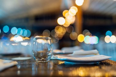 Şarap kadehleri ve çiçekli yemek masası, düğün için mükemmel, zarif bir parti ya da açık hava kutlaması için. Sıcak ışıklar ve yumuşak bokeh samimi ve lüks bir atmosfer yaratır..