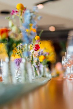 Şarap kadehleri ve çiçekli yemek masası, düğün için mükemmel, zarif bir parti ya da açık hava kutlaması için. Sıcak ışıklar ve yumuşak bokeh samimi ve lüks bir atmosfer yaratır..