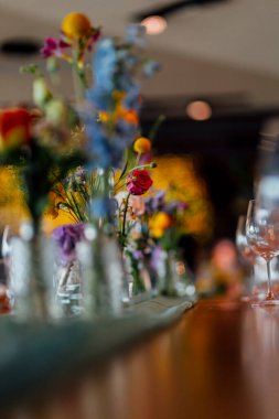 Şarap kadehleri ve çiçekli yemek masası, düğün için mükemmel, zarif bir parti ya da açık hava kutlaması için. Sıcak ışıklar ve yumuşak bokeh samimi ve lüks bir atmosfer yaratır..