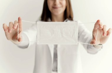 Yüzünde sağlık maskesi olan beyaz önlüklü yakışıklı bir doktor. Koronovirüs salgını. Salgının sonu. Mesafeyi koru. Koronovirüse karşı özel beyaz maske