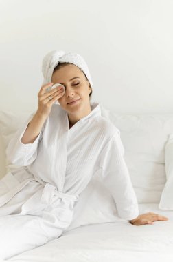 Yüzünde gülümseme olan güzel bir kız evdeyken yüzüne krem sürüyor. Doğal kozmetik. Dermatoloji. Sağlıklı yaşam tarzı.