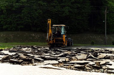 Sarı kazıcı traktör kovasıyla asfalt kazıyor. Buldozer yoldaki asfaltı söker. yol onarımları