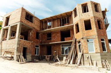 Bir tuğla ev inşa etme süreci. İnşaatçılar binanın tepesinde çalışıyor. Çatı inşaatı. kır evi yapım aşamasında