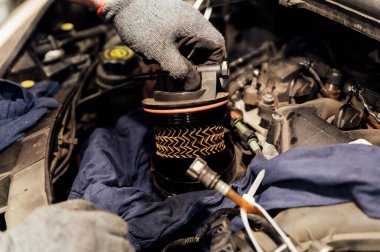 Kirli yakıt filtresini değiştiren araba tamircisinin ellerine yakın çekim. Arabada filtre değişimi var. Araba tamir servisi. kullanılmış yakıt filtresi