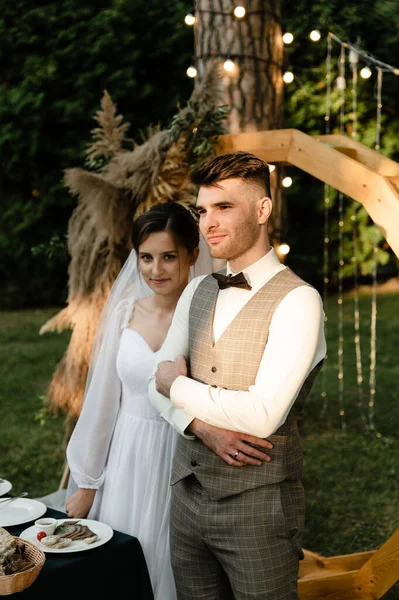 Fiatal Menyasszony Vőlegény Háttérben Egy Boltív Egy Esküvői Asztal Étellel — Stock Fotó