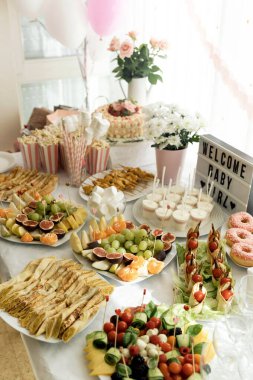 Bebek partisi pasta masası, kır bahçesi dekorasyonu. Kızlar için bebek partisi. Odadaki lezzetli ikramlar balonlarla süslenmiş.