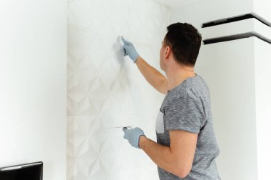 Duvarları sıvamak ve boyamak için hazırlık. Usta sıva ya da dolgu yapar. Evde tamirat var. Erkek sahibi duvarı alçılıyor.