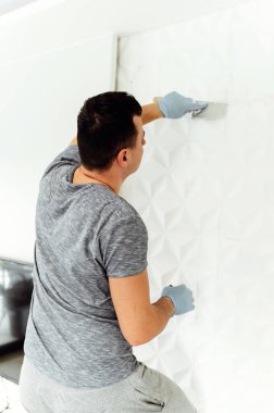 Duvarları sıvamak ve boyamak için hazırlık. Usta sıva ya da dolgu yapar. Evde tamirat var. Erkek sahibi duvarı alçılıyor.