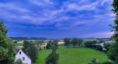 Yeşil çimenleri ve bulutlu gökyüzü olan güzel bir manzara.