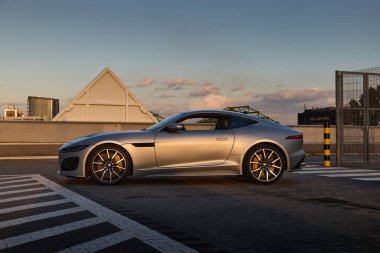 Jaguar F tipi coupe, otoparkta, batan güneşin ışınlarında. Yan görüş. Mat boyalı araba. 5.0L motor, 575 beygir. Katowice, 17 Haziran 2022